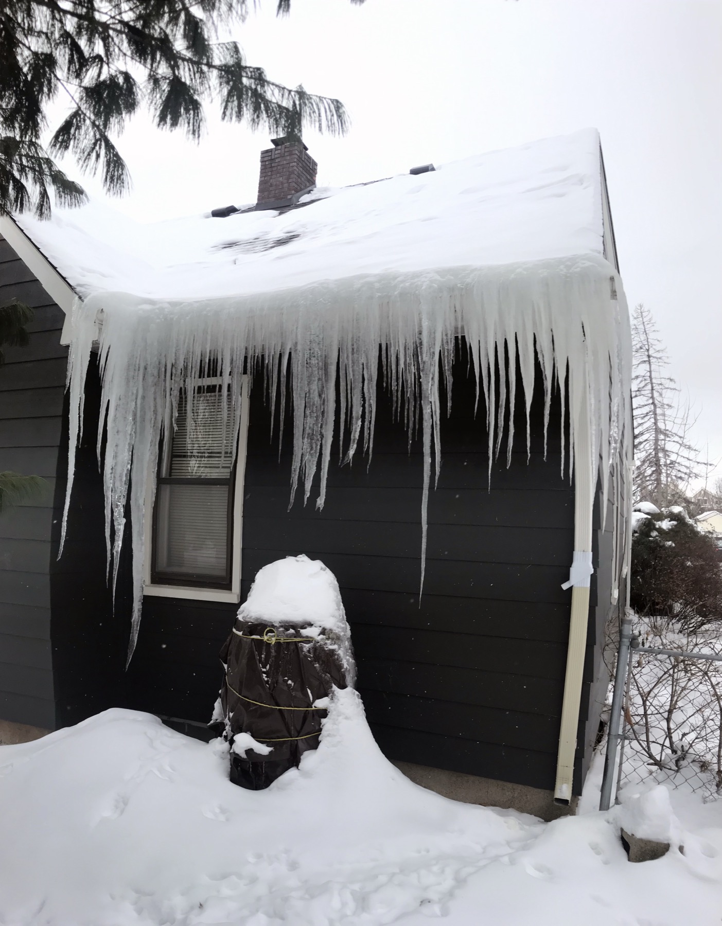 Heavy ice dam and icicles along a snowy roof edge